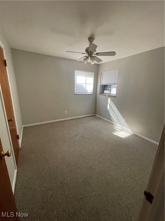 Carpeted spare room with baseboards and ceiling fan