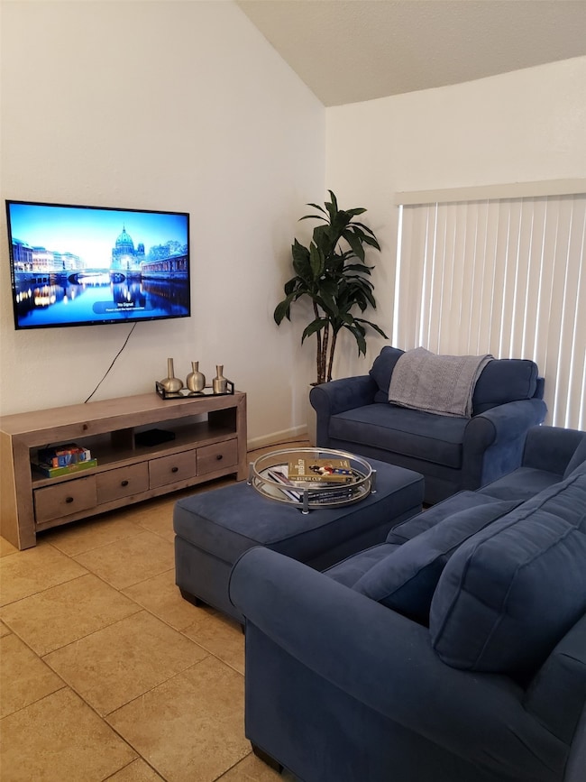 The living room features cozy blue sofas, a wall-m