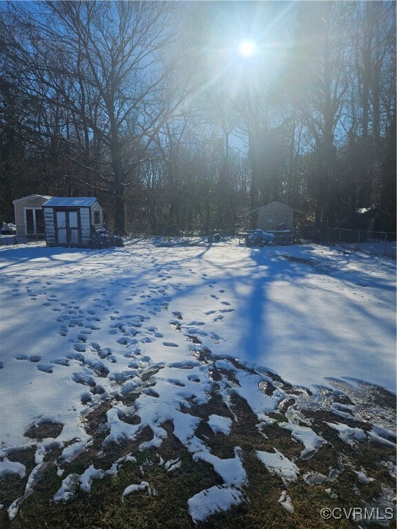 Yard layered in snow with a storage shed