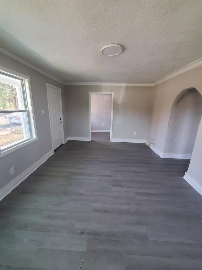 Spare room featuring arched walkways, a textured c