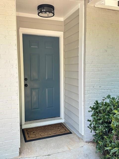 Doorway to property featuring brick siding