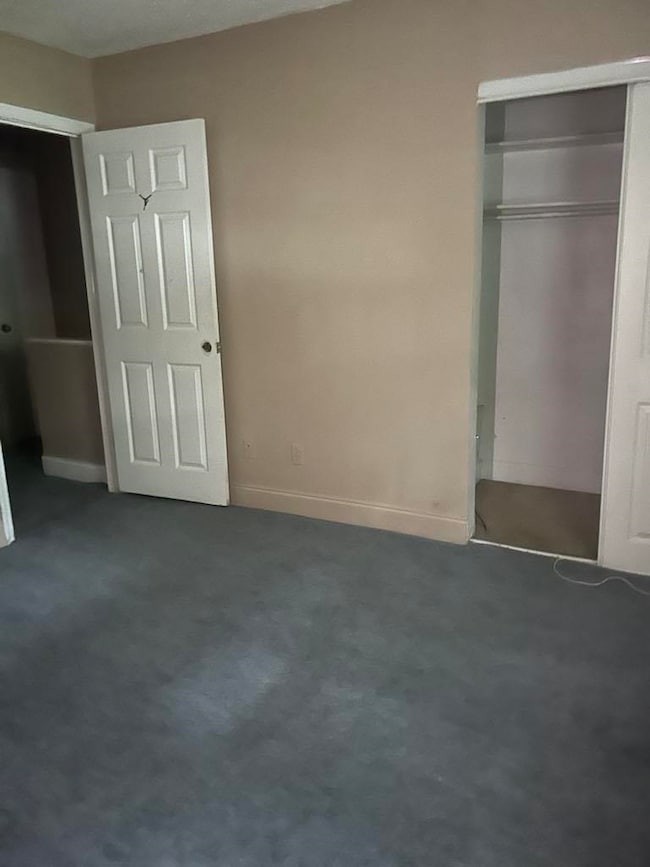 Unfurnished bedroom with dark carpet and a closet