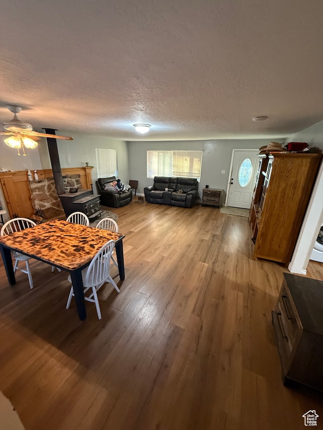 Dining area featuring light wood-style flooring, ceiling fan, a textured ceiling, and a fireplace