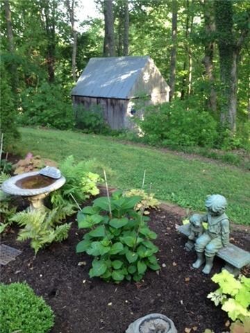 The Back of Home has a Serene Setting, with Flowers, Trees and a Storybook Garden Shed.  