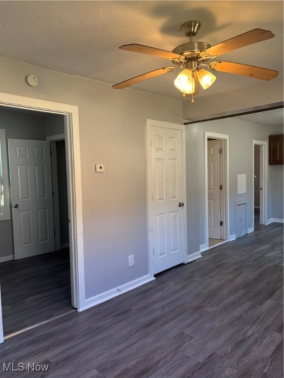 Unfurnished bedroom featuring dark wood-style floors, a closet, and a ceiling fan