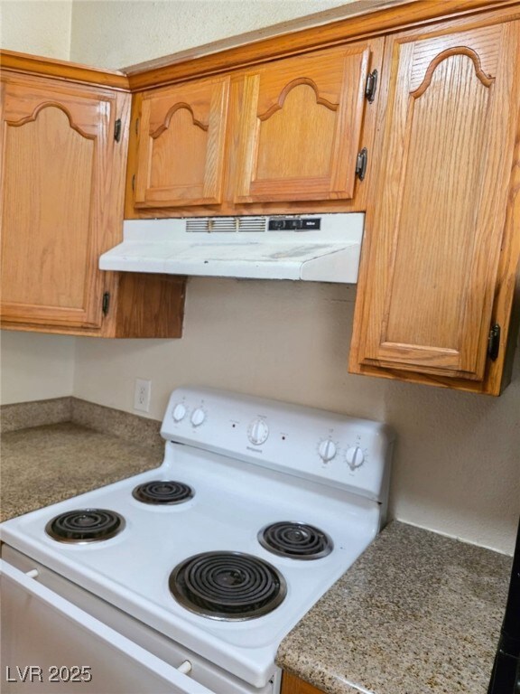 Kitchen with white electric stove, under cabinet r