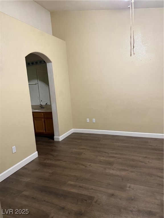 Unfurnished room with arched walkways, baseboards,