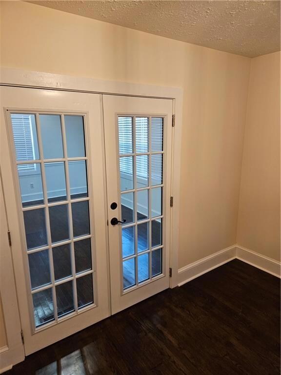 Doorway with baseboards, a textured ceiling, dark 