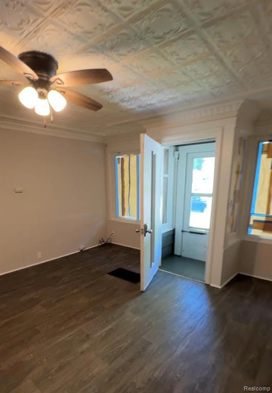 Spare room featuring dark wood-type flooring, an ornate ceiling, ornamental molding, and a ceiling fan