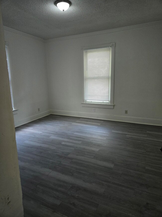 2nd bedroom featuring a textured ceiling, dark wood-style flooring, ornamental molding, and baseboards