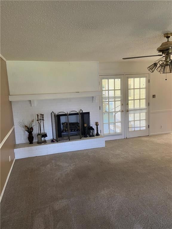 Unfurnished living room featuring a fireplace, french doors, a textured ceiling, ceiling fan, and carpet flooring