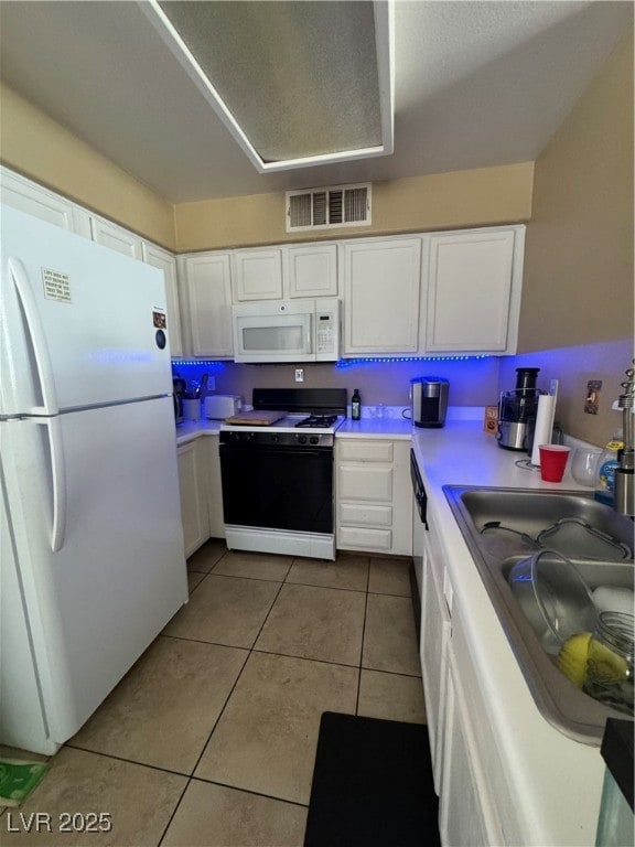 Kitchen featuring fridge, range, white cabinetry,