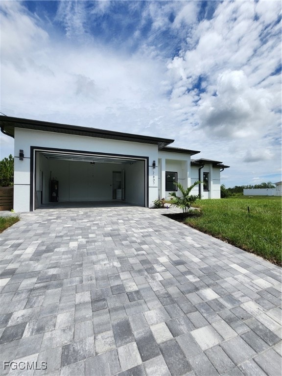View of front facade with decorative driveway, an attached garage, and stucco siding