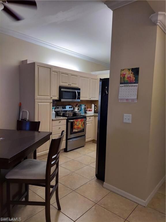 Kitchen featuring appliances with stainless steel finishes, crown molding, ceiling fan, and light tile patterned floors