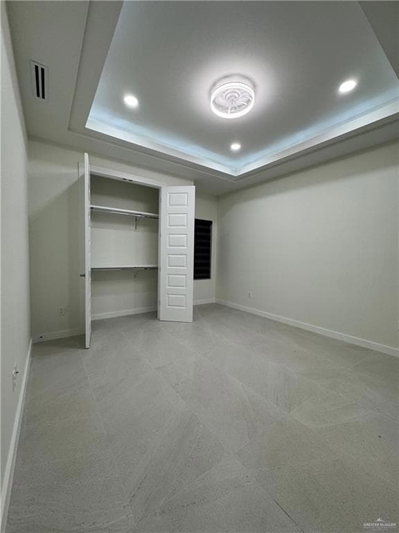 Unfurnished bedroom with a tray ceiling, recessed lighting, and a closet