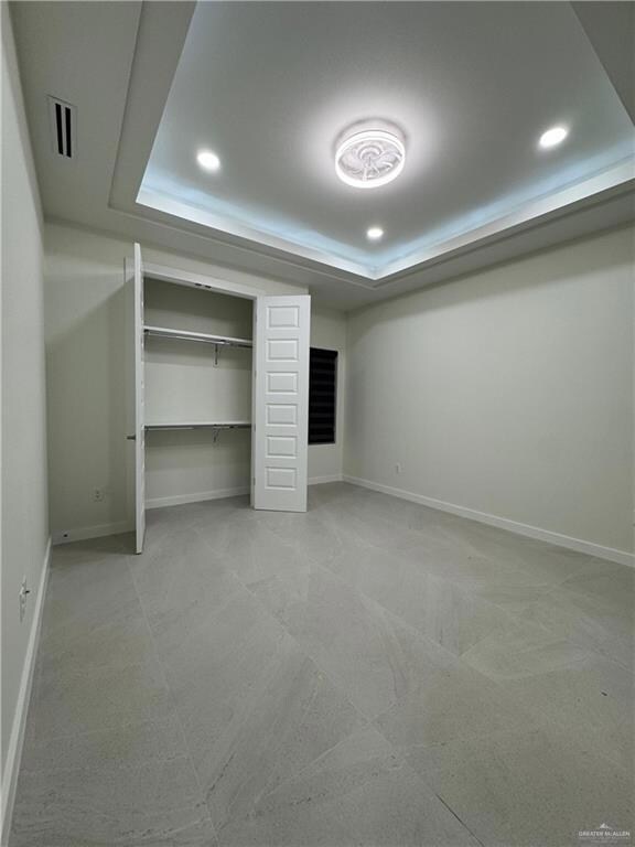 Unfurnished bedroom with a tray ceiling, recessed lighting, and a closet