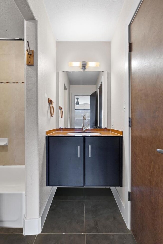 Full bathroom featuring vanity, dark tile patterned floors, and shower / tub combination