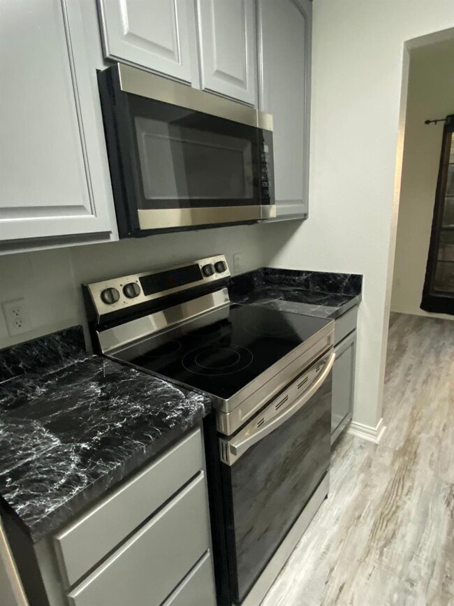 Kitchen with dark stone countertops, light wood-ty