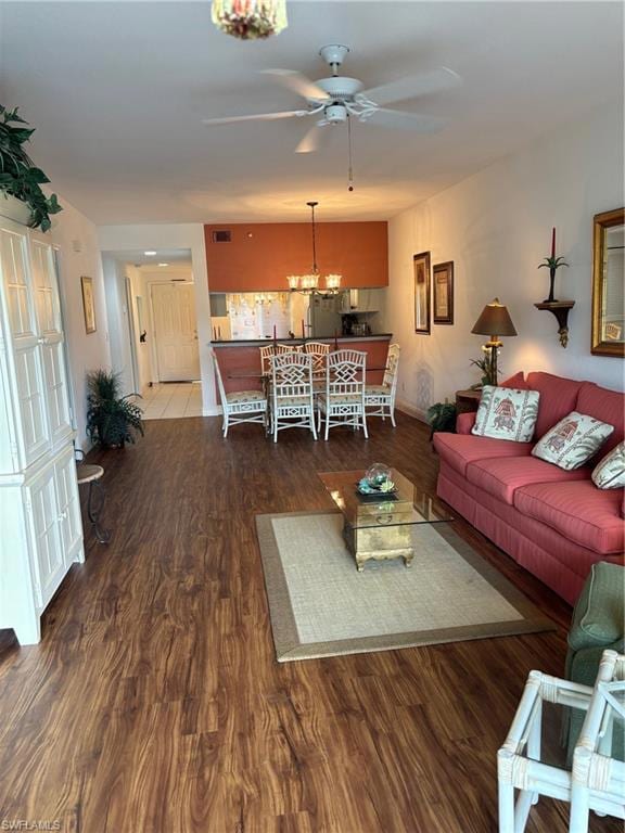 Living room featuring ceiling fan with notable chandelier and hardwood / wood-style floors