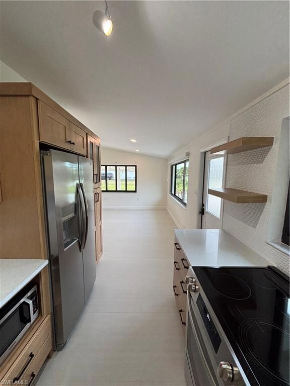 Kitchen featuring stove, fridge, and lofted ceilin