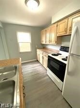 Kitchen with white electric stove, wood-type flooring, light brown cabinetry, and fridge