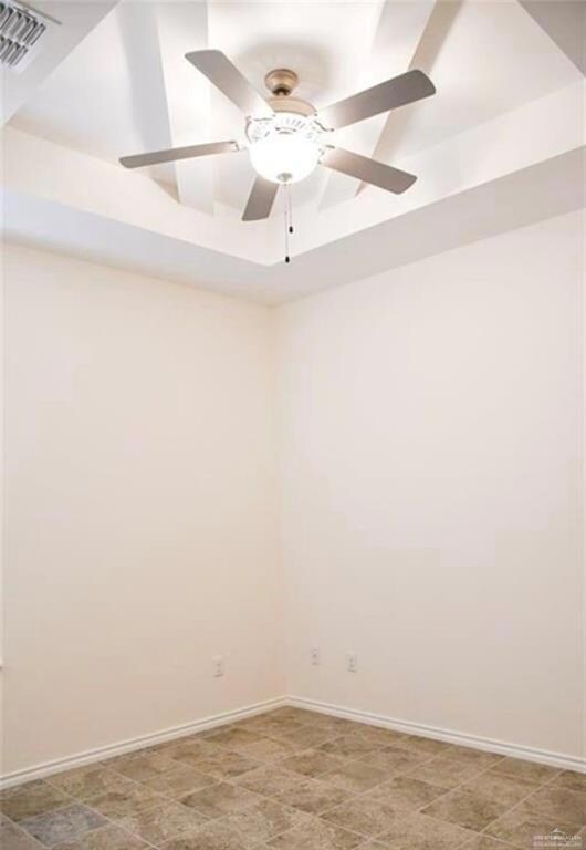 Empty room with ceiling fan and a tray ceiling