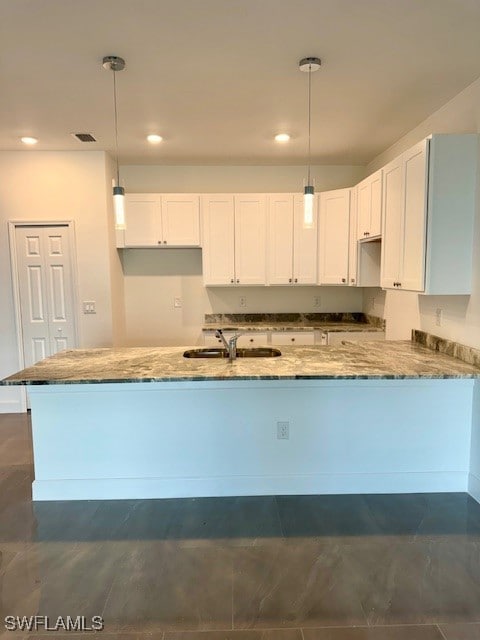 Kitchen with stone countertops, a sink, white cabi