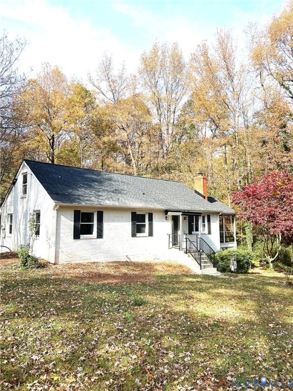 Ranch-style home with a chimney, a shingled roof, and a front lawn