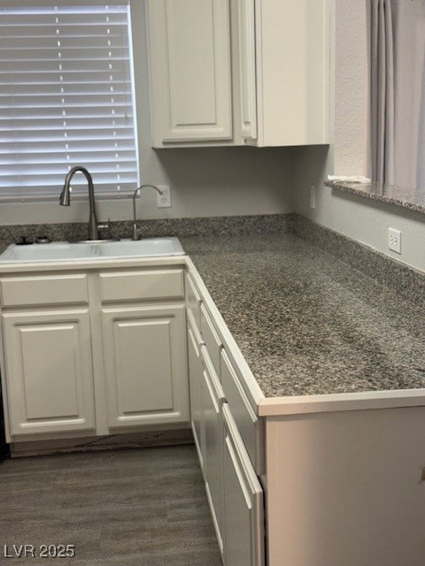 Kitchen featuring dark countertops and white cabinetry