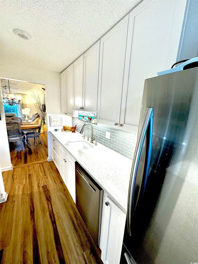 Kitchen with white cabinetry, sink, light hardwood