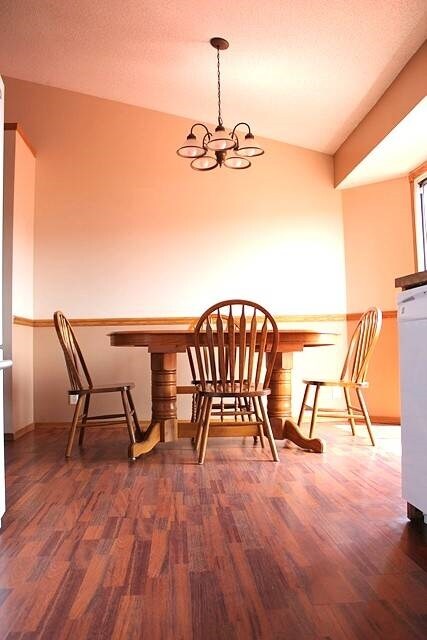 Dining room has wood laminate floors, vaulted ceil