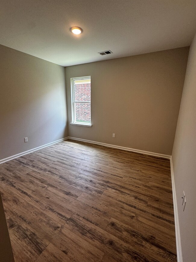 Bedroom with dark wood-style floors and baseboards