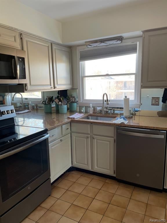 Kitchen featuring stainless steel appliances, light tile patterned floors, and light stone counters