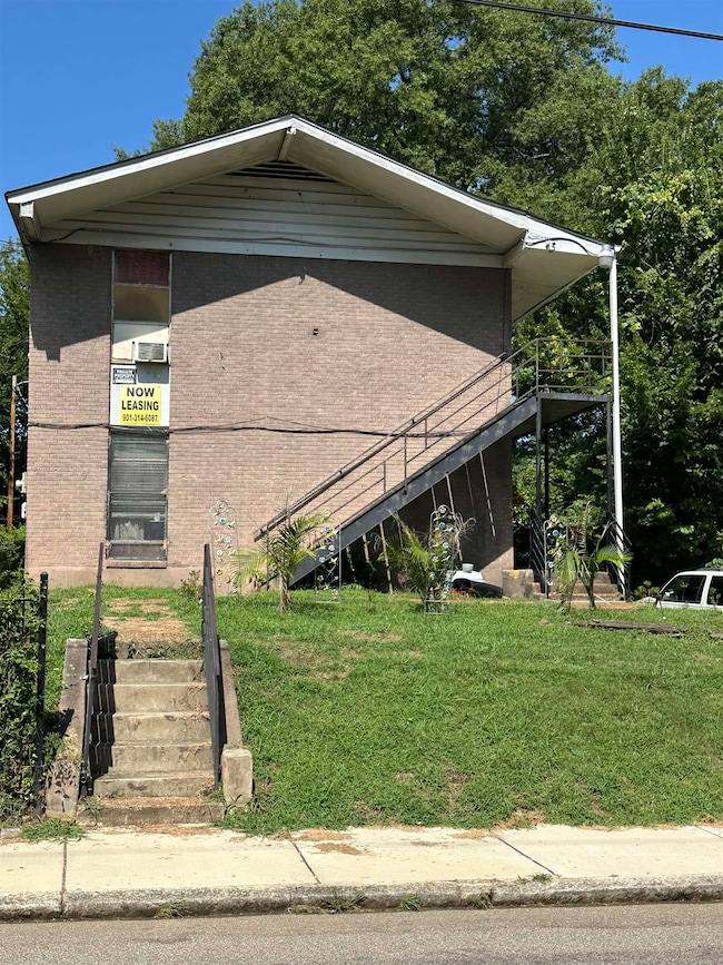 View of side of home with stairway, brick siding, and a lawn