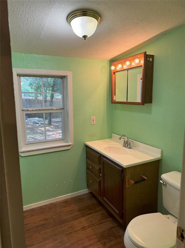 Bathroom with vanity, a textured ceiling, wood-typ