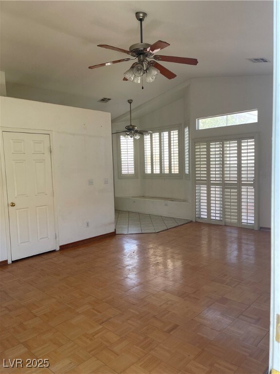 Spare room featuring vaulted ceiling, ceiling fan,