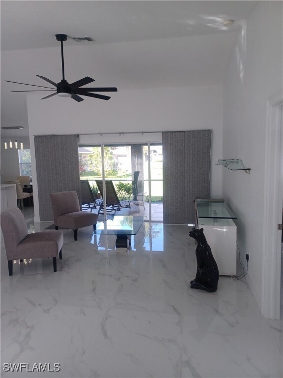 Living room with ceiling fan and marble finish flo