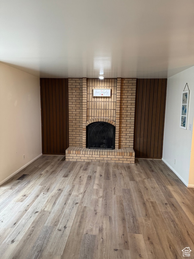 Unfurnished living room featuring a brick fireplace and light hardwood / wood-style flooring