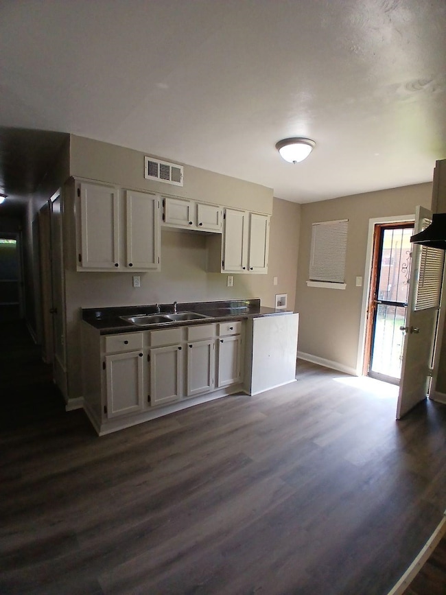 Kitchen featuring dark wood-type flooring, white cabinets, and dark countertops