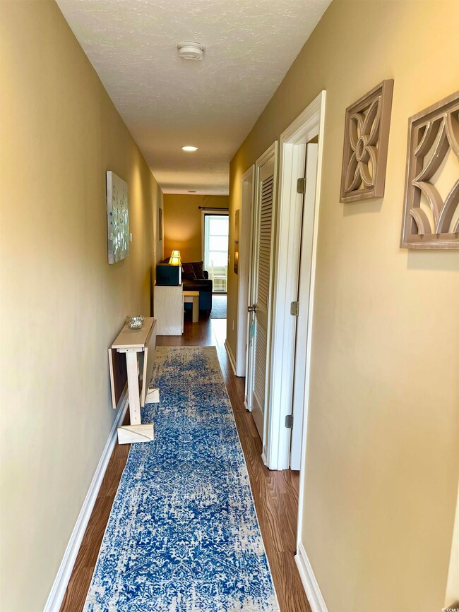 Hall with a textured ceiling and dark wood-type fl