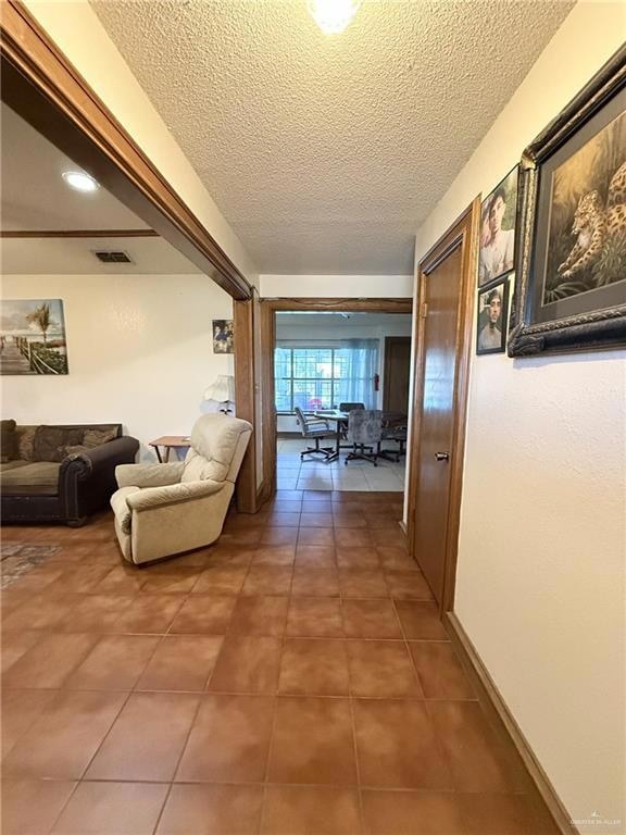 Corridor featuring light tile patterned floors and a textured ceiling