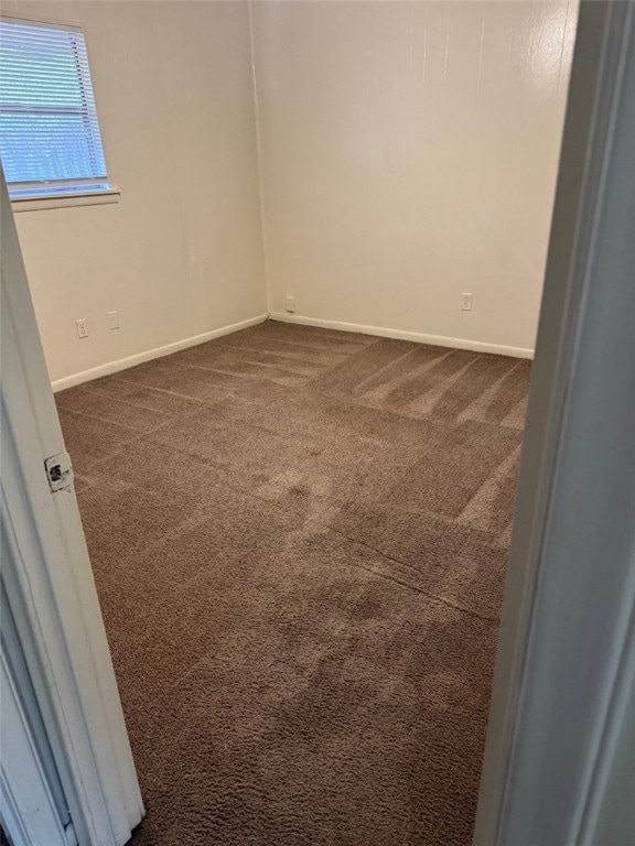 Unfurnished room featuring dark colored carpet and
