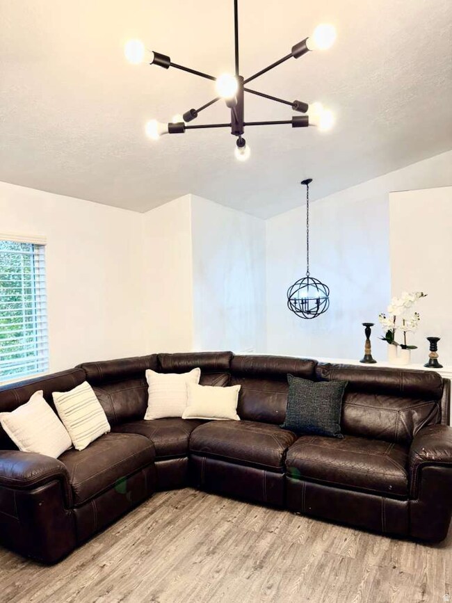 Living room featuring light wood finished floors, a textured ceiling, and a chandelier