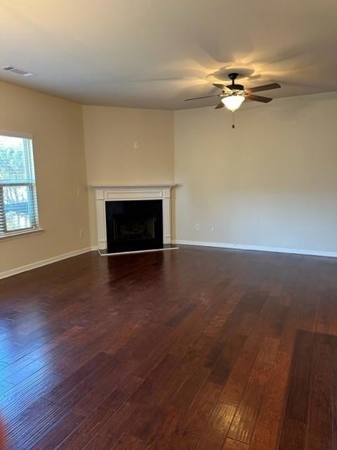 Unfurnished living room featuring a fireplace, dark wood-type flooring, and a ceiling fan