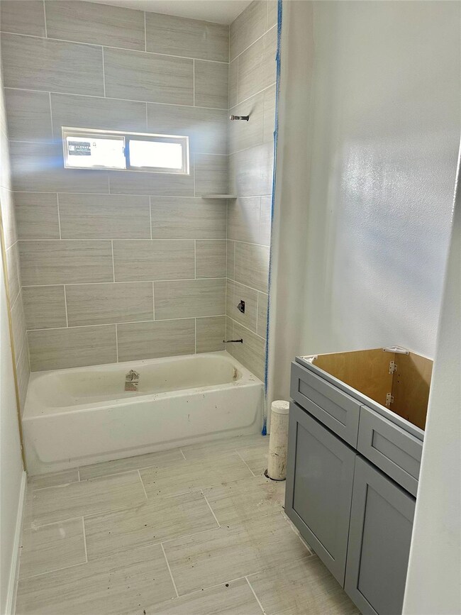 Bathroom with tiled shower / bath combo, tile floo