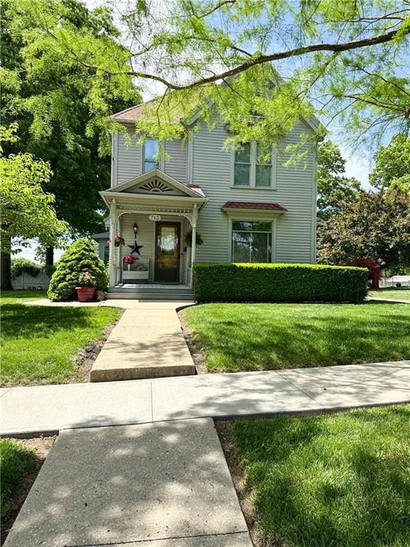 Victorian house featuring covered porch and a front yard