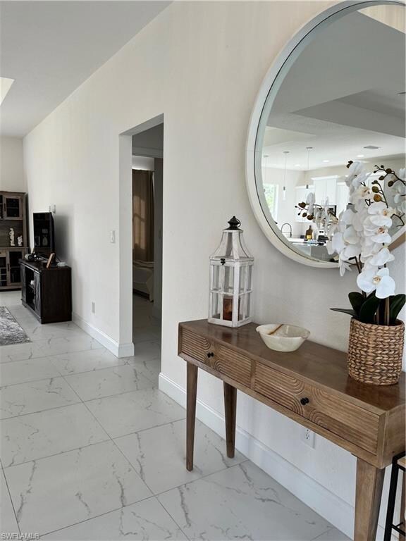 Hall with arched walkways, baseboards, and marble finish floor