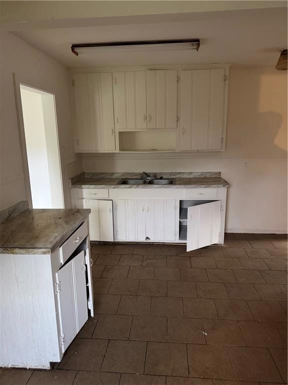 Kitchen with open shelves, a sink, and white cabinetry