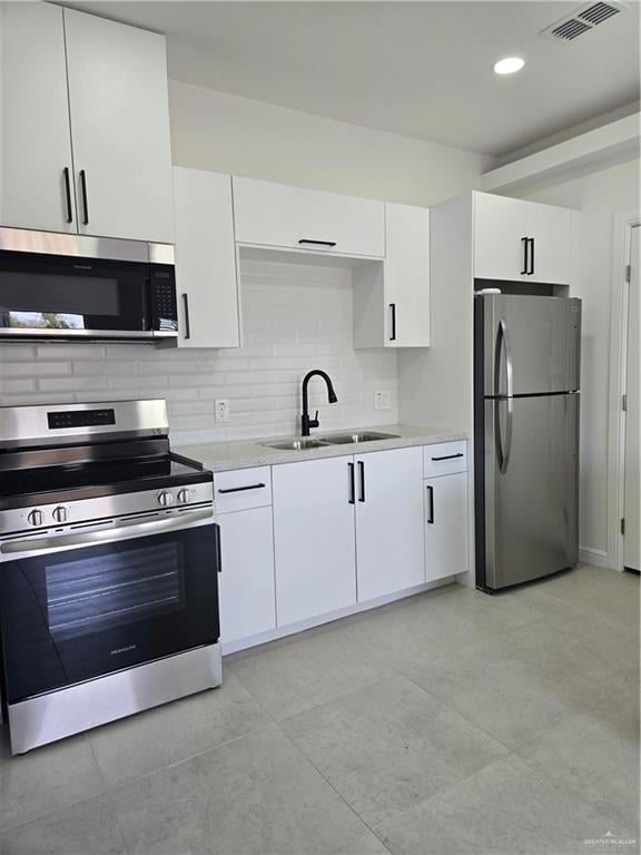 Kitchen featuring range, fridge, a sink, white cabinetry, and decorative backsplash