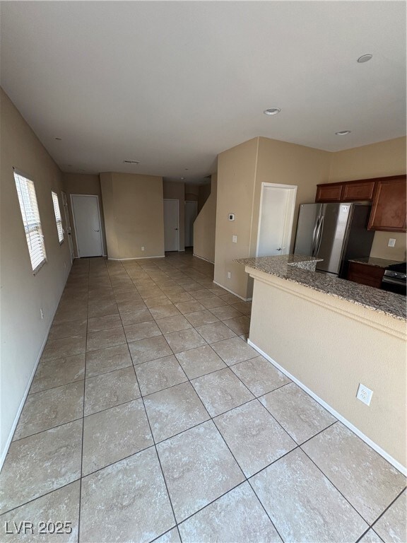 Kitchen with fridge, light tile patterned floors,